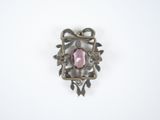 a pink stone in the center of a silver broochle