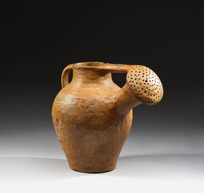 un vieux vase marron troué, posé sur une table
