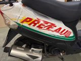 a white and green moped with a red and yellow sticker on it