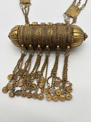 un gros plan d'un collier posé sur une surface blanche, avec des chaînes