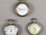 Trois types différents de montres de poche sont exposés sur un fond gris