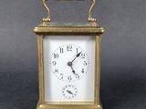 a small brass clock with a white face on a table