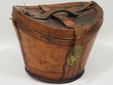 an old wooden box with a leather handle on a white surface
