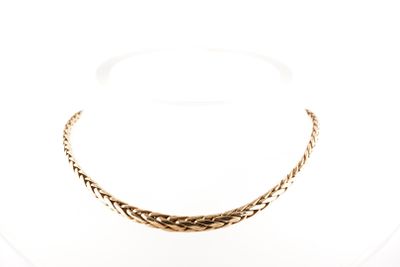 gros plan d'un collier en or sur une surface blanche