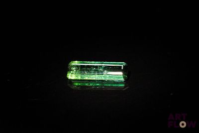 un gros plan d'un morceau de verre vert posé sur une surface noire