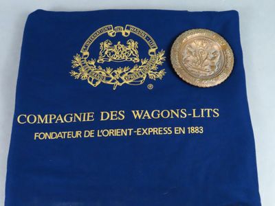un sac bleu contenant une pièce d'or et une autre pièce posée dessus