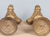 two antique brass candlesticks on a wooden table with a blue wall in the background