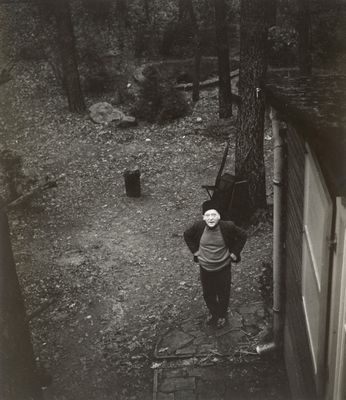 black and white photograph of a woman standing in a yard next to a dog