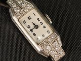une montre en argent sertie de diamants, posée sur un fond noir