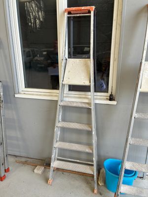 trois échelles adossées au mur près d'une fenêtre