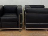pair of black leather lounge chairs with chrome legs
