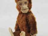 un petit singe en peluche assis par terre