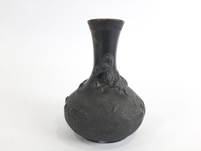 un vase noir posé sur une surface blanche