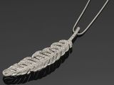 un pendentif en forme de plume argentée avec une chaîne, sur fond noir
