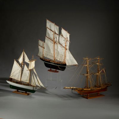 trois maquettes de bateaux exposées sur une table