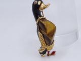 a small black and gold duck with a red shoe on it ' s feet