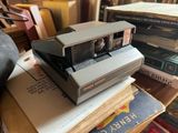 a polaroid camera sitting on top of a stack of books