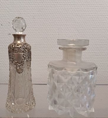 deux bouteilles en verre posées l'une à côté de l'autre sur une étagère en verre