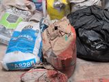a cat sitting on the floor next to a pile of garbage