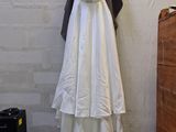 a white dress hanging on a wall next to a dresser