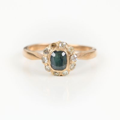 a close up of a gold ring with a green and white diamond