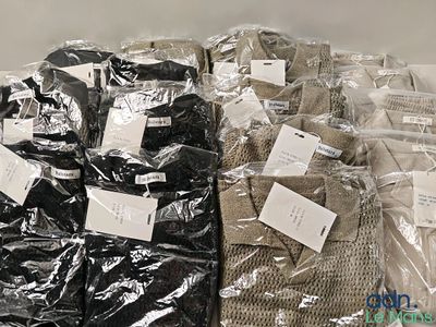 plusieurs sacs de vêtements posés sur une table, sur lesquels sont apposées des étiquettes