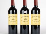trois bouteilles de vin rouge posées l'une à côté de l'autre sur une surface blanche