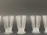 six clear glass vases lined up on a black surface