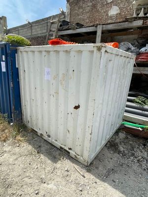 un conteneur blanc posé dans la terre à côté d'un conteneur bleu