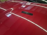 a shiny red car with a black emblem on the hood
