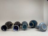 five blue and white vases sitting on a white surface