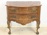 une vieille commode en bois avec des poignées en laiton, posée sur un sol en marbre