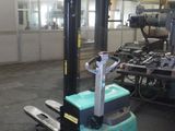 un chariot élévateur bleu dans un entrepôt, à côté d'autres machines