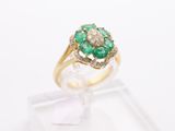 an emerald and diamond ring on a clear display stand