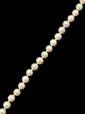 un collier de perles avec un fermoir en or sur fond noir