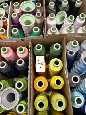 many spools of thread in boxes on a table