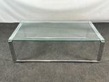 une table basse en verre avec des pieds chromés et un plateau en verre