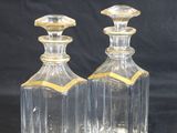 deux bouteilles en verre transparent ornées de bordures dorées sur fond noir