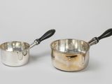 pair of silver saucepans with black handles on a white background