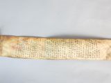 an old scroll with writing on it sitting on a white surface