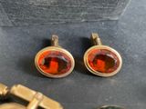 two pairs of red and gold earrings sitting on top of a table
