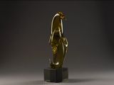 une statue en or représentant une femme debout sur un socle noir