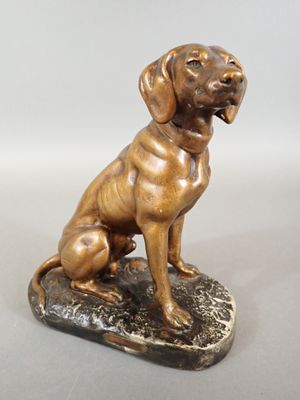 bronze statue of a dog sitting on a rock on a white background