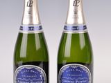 two bottles of sparkling wine sitting next to each other on a table