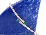 un gros plan sur une pierre bleue sur laquelle est posé un bracelet orné d'un diamant et d'une émeraude