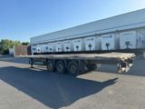 a large flatbed trailer parked in front of a building
