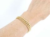 someone is wearing a gold bracelet with a chain on their wrist