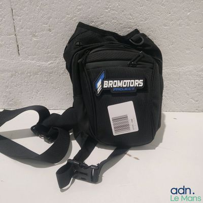 un petit sac noir sur lequel est accrochée une étiquette avec un nom