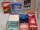 several books on a bed with a white sheet in the background