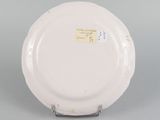 underside view of a white plate with writing on it on a gray surface